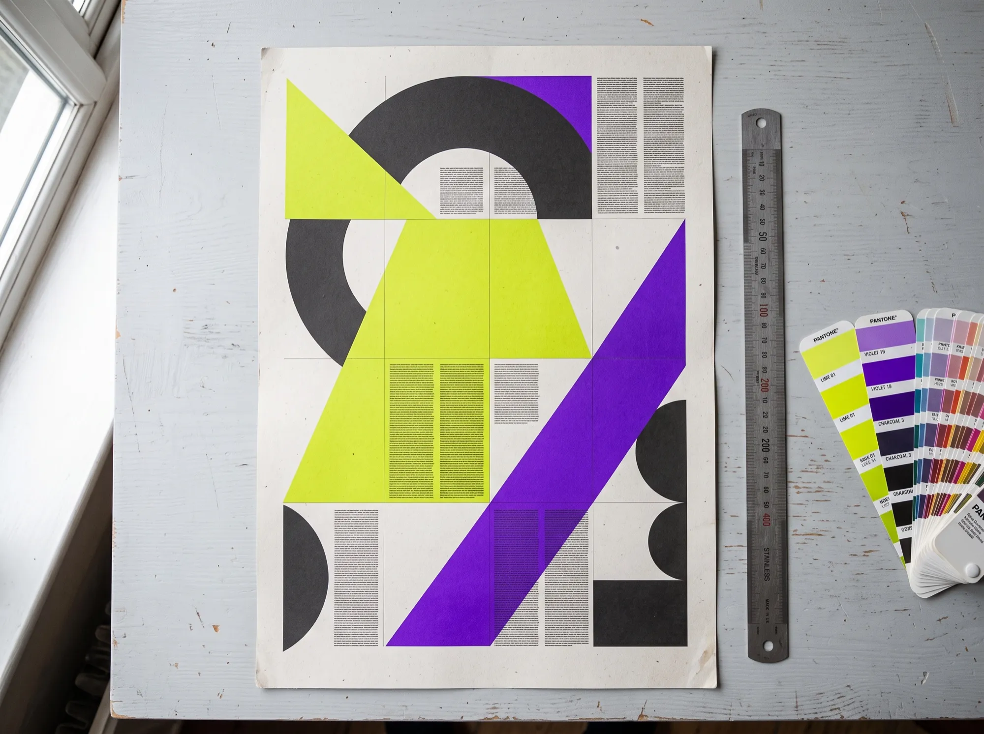 Platzhalterbild: Plakat mit geometrischen Formen in Lime und Violett auf einem Schreibtisch